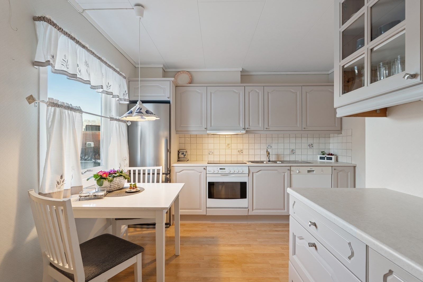 Innredningen har profilerte fronter, enkelte glassfronter og laminert benkeplate med nedfelt oppvaskkum i stål Galleribilde