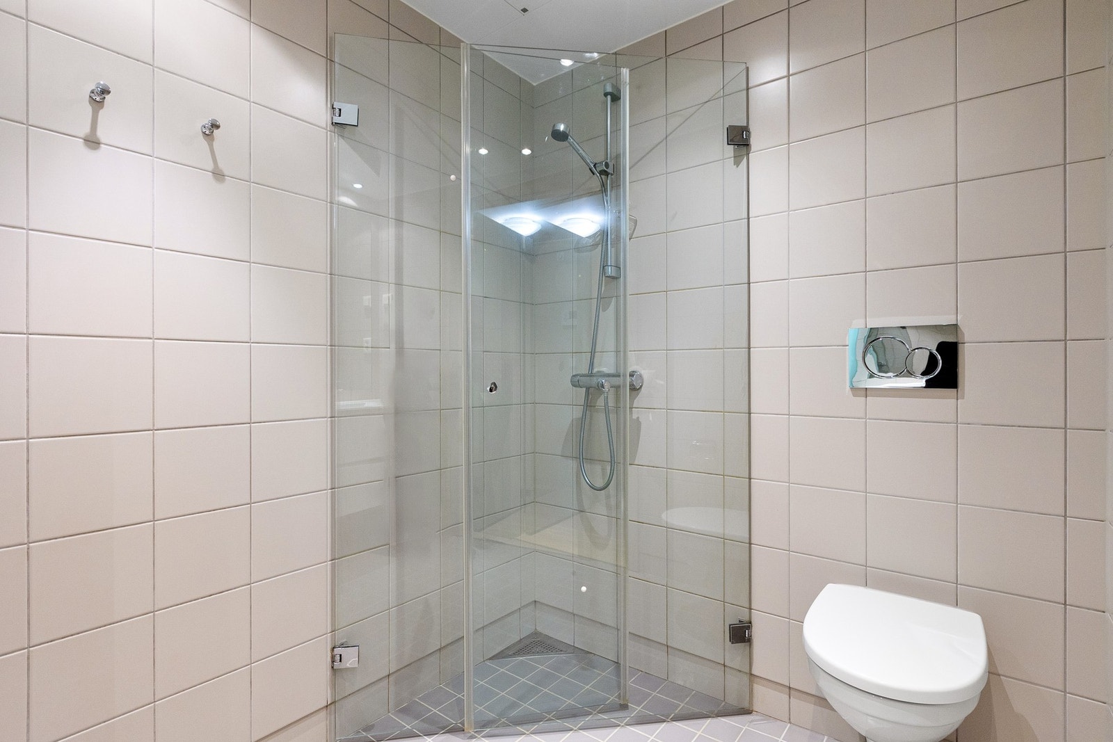 Videre er badet utstyrt med dusjhjørne i glass, vegghengt toalett og downlights i himling. Galleribilde