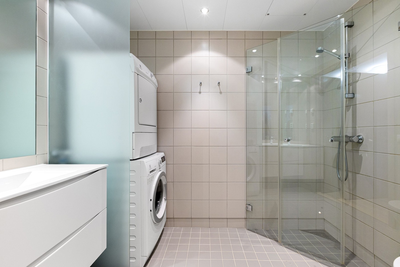 Flislagt bad med gulvvarme, servantinnredning og opplegg for vaskemaskin og tørketrommel (som følger med). Galleribilde