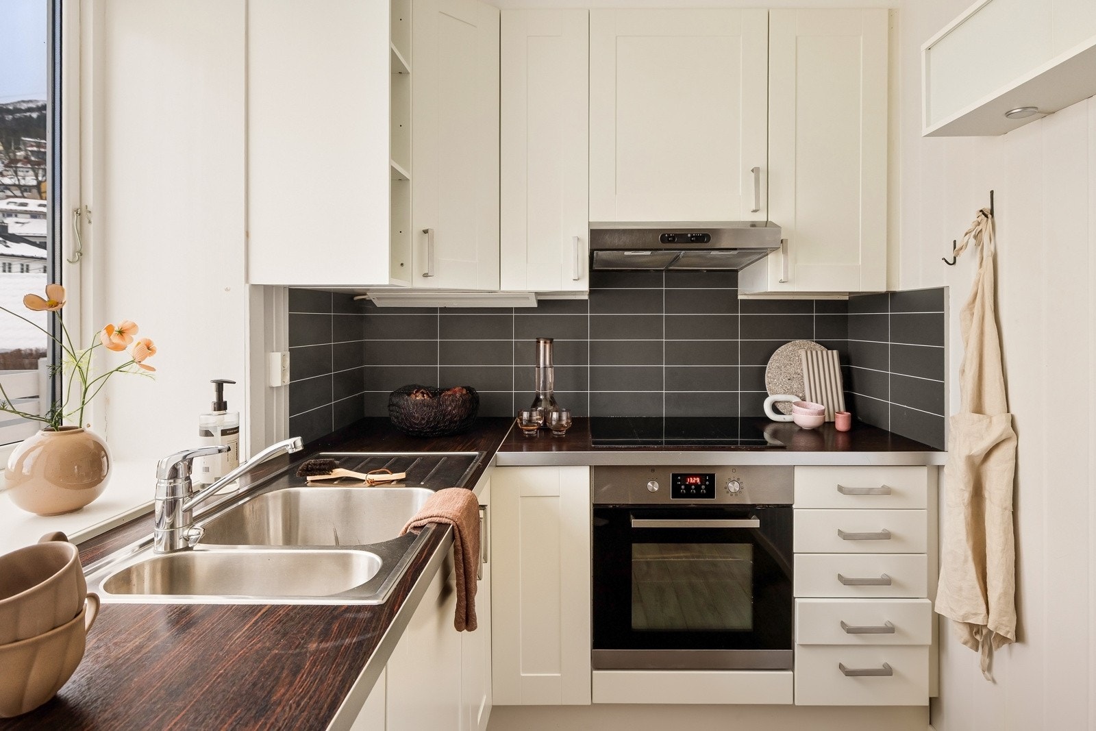 Stilsikkert kjøkken med lyse, profilerte skapfronter og medfølgende hvitevarer. Galleribilde