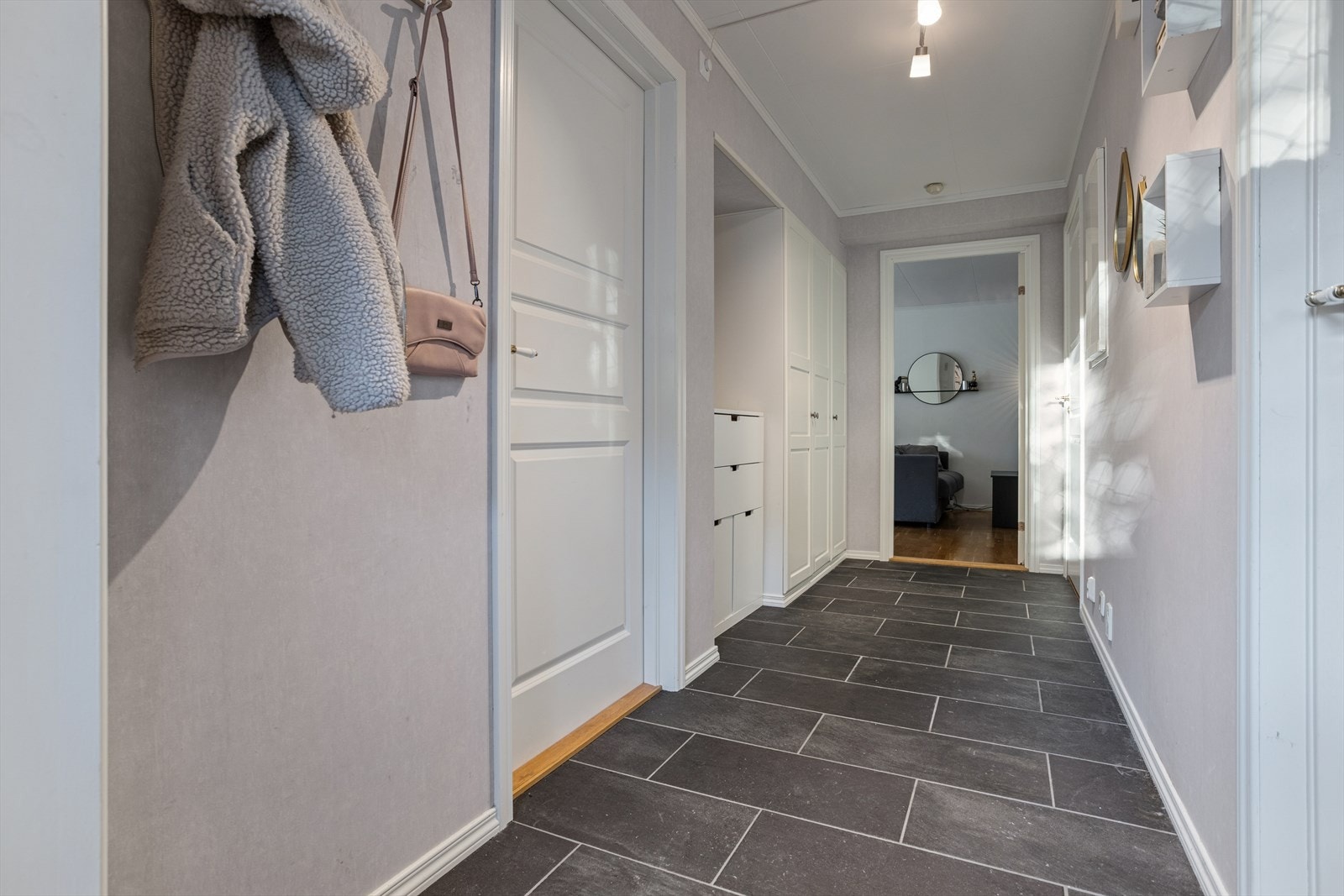 Romslig entré på ca. 7,6 m² med flislagt gulv over varmekabler. God garderobeplass og et rent, moderne uttrykk med lyse flater. Galleribilde