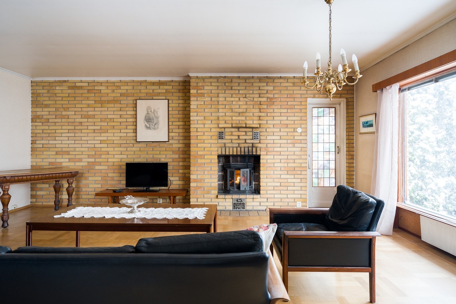 Teglsteinsvegger gir et solid preg til stuen, mens peisen sørger for varme og hygge. (Merk: Pipen er ikke i bruk da eier har fått fritak, se salgsoppgaven). Galleribilde