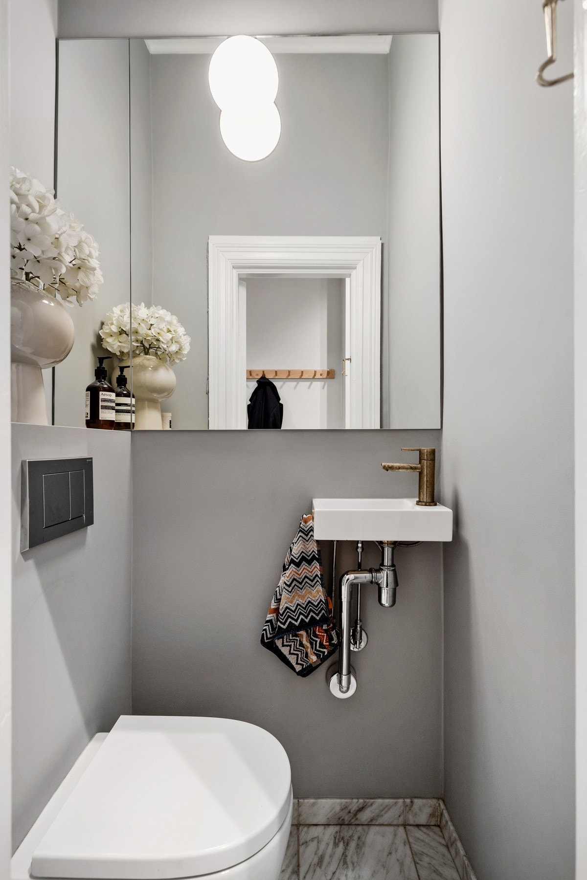 Toalettrommet har en praktisk tilknytning til entréen og fremstår som stilrent og funksjonelt. Rommet er innredet med vegghengt toalett, servant og speil, og har flislagt gulv med varmekabler. Galleribilde