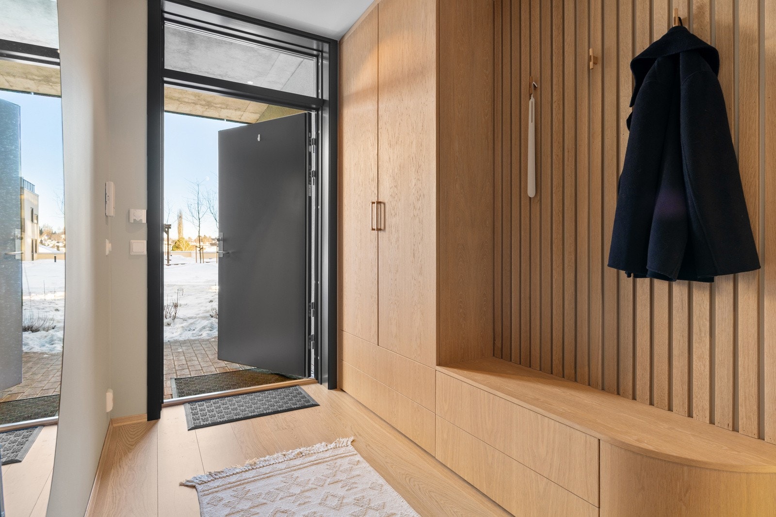 En ryddig og gjennomtenkt entré med smarte oppbevaringsmuligheter og moderne detaljer. Galleribilde