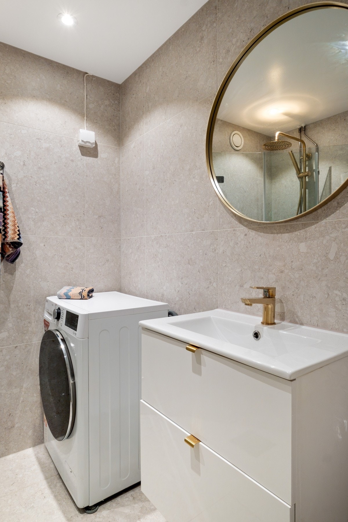 Innredningen på badet består av baderomsmøbel med romslige skuffer og heldekkende servant, speil på veggen over servanten og opplegg for vaskemaskin. Galleribilde