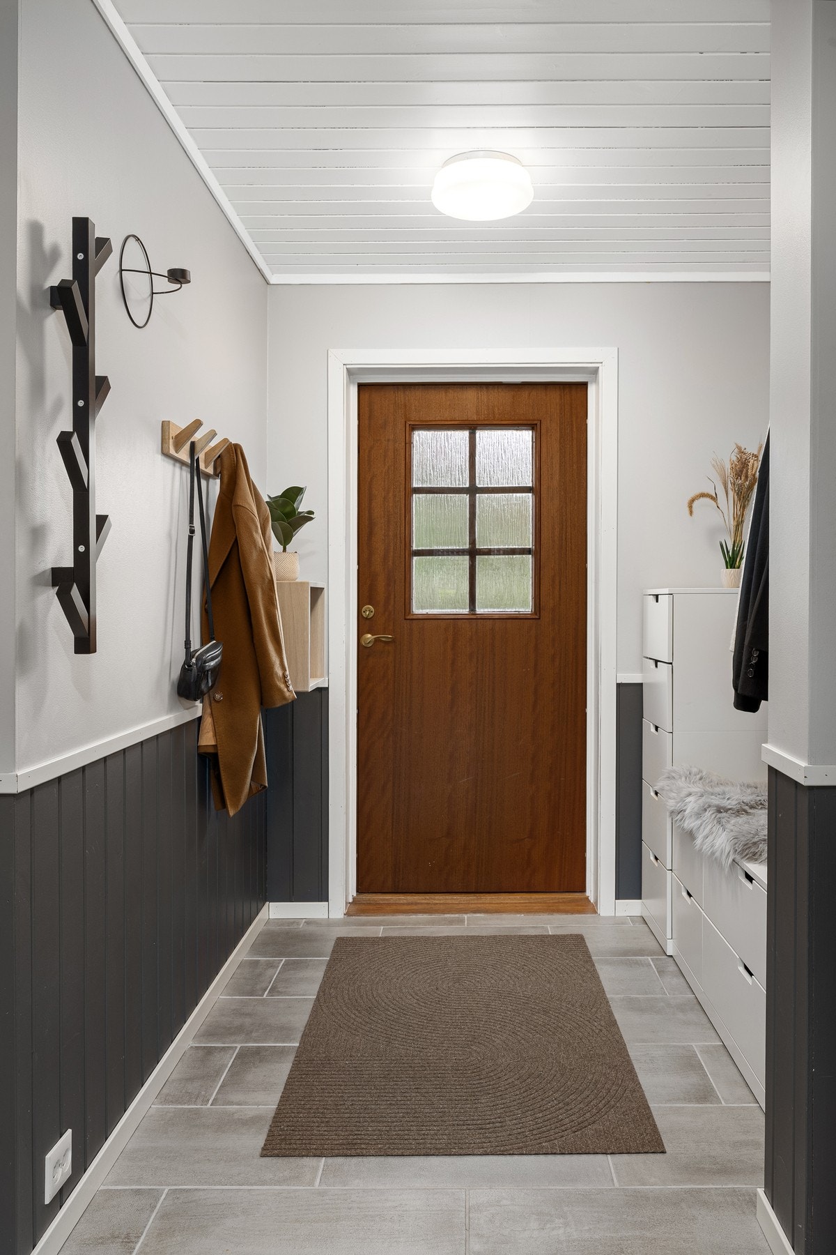 Boligens entré har fliser på gulv og malte veggflater. Galleribilde