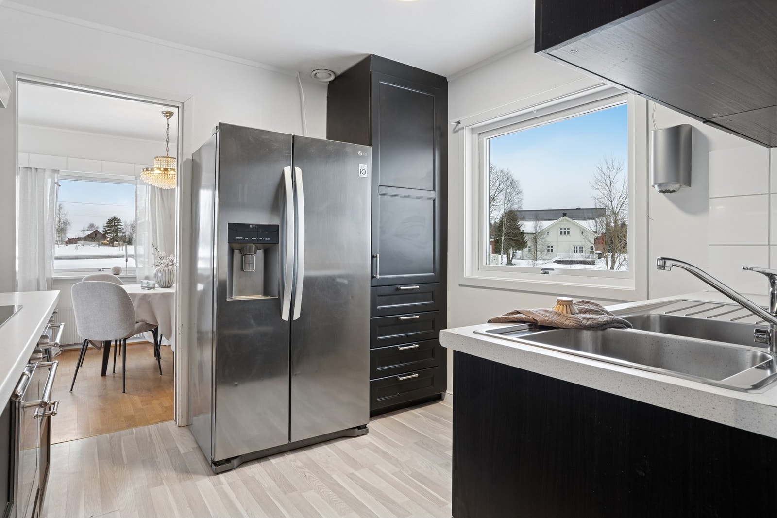 Kjøkkeninnredning fra 2015 med profilerte fronter. Benkeplater av laminat med nedfelt oppvaskkum med ett-greps kran. Fliser mellom kjøkkenbenk og overskap. Benkeskapsbelysning og stikkontakter under overskap. Galleribilde