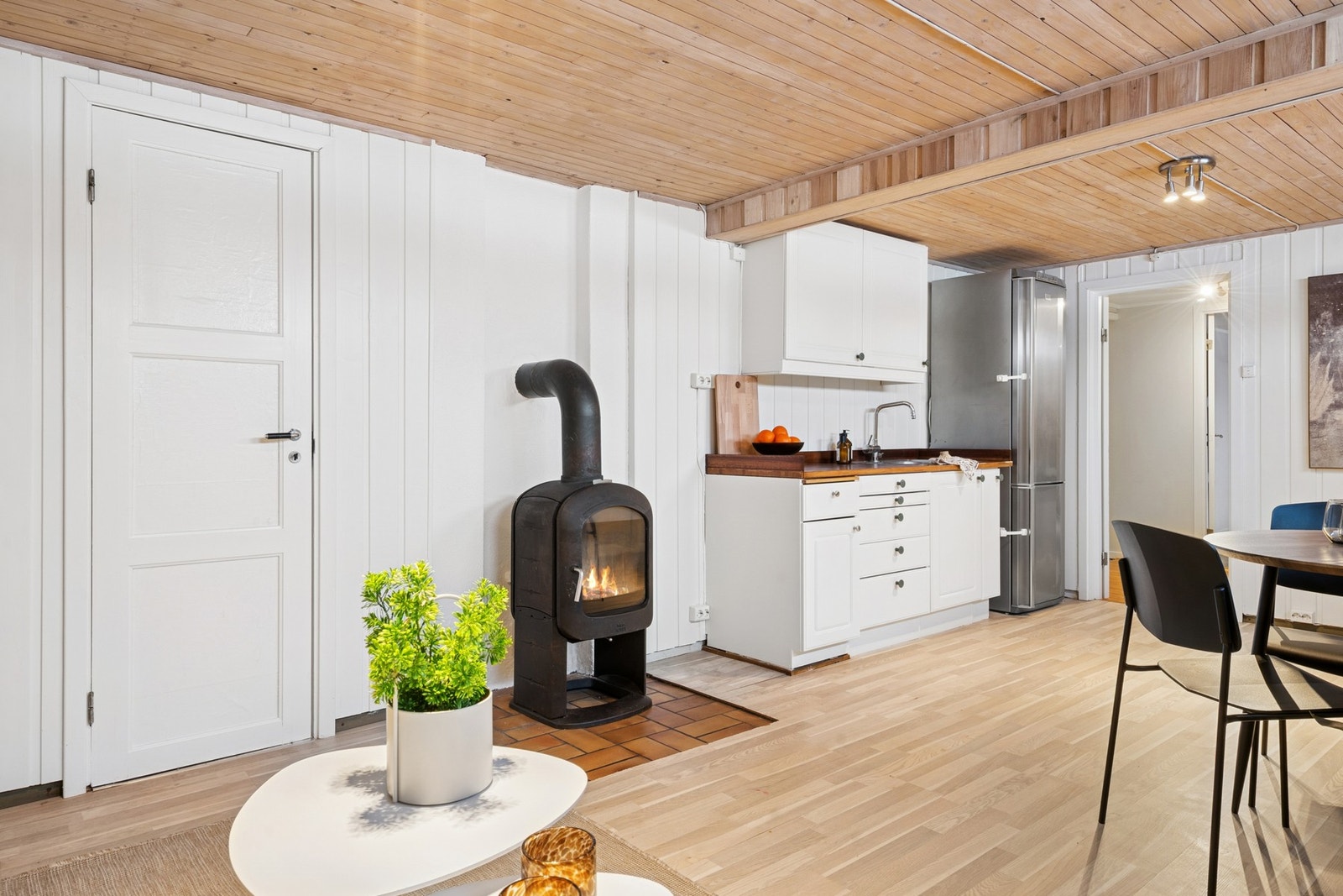 Disponibelt rom i kjeller brukt som stue. Åpen kjøkkenløsning mot stue med profilerte fronter fra ukjent årstall. Benkeplater av tre med nedfelt oppvaskkum med ett-greps kran. Stikkontakter på vegg over benkeplater. Frittstående kjøleskap med fryser og fr Galleribilde