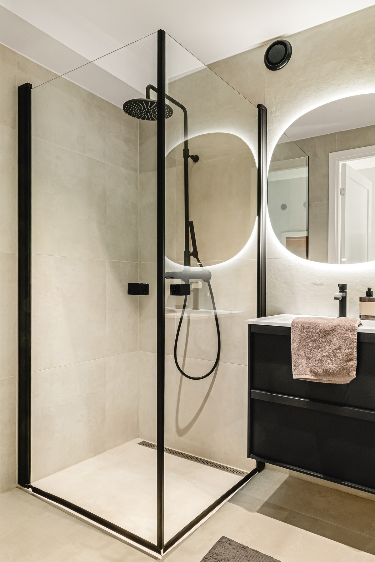 Badet inneholder vegghengt toalett, helstøpt servant, skuffer under servant med slette fronter og dusjdører i klart glass. Galleribilde