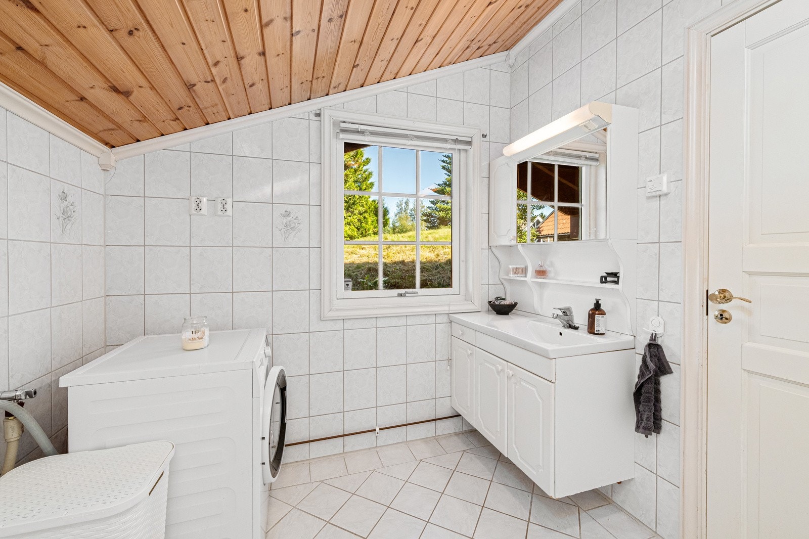 Badet i utleieleiligheten har fliser på gulv og vegger og varme i gulv. Hvit profilert baderomsinnredning Galleribilde