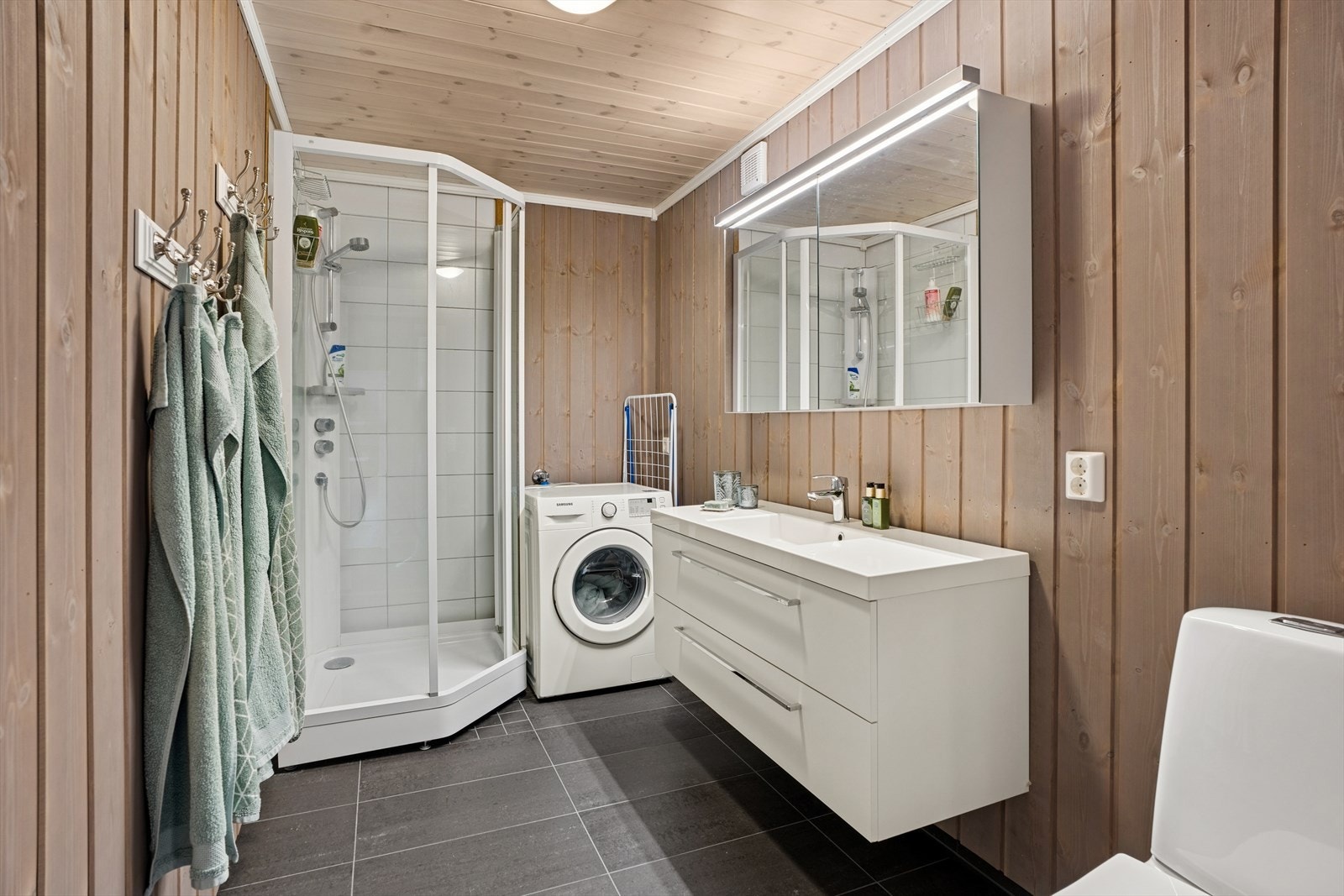 Baderommet har flislagt gulv med elektriske varmekabler, og veggene er kledd med fabrikkbeiset furu skyggepanel - med unntak av dusjhjørnet, som er flislagt. Galleribilde