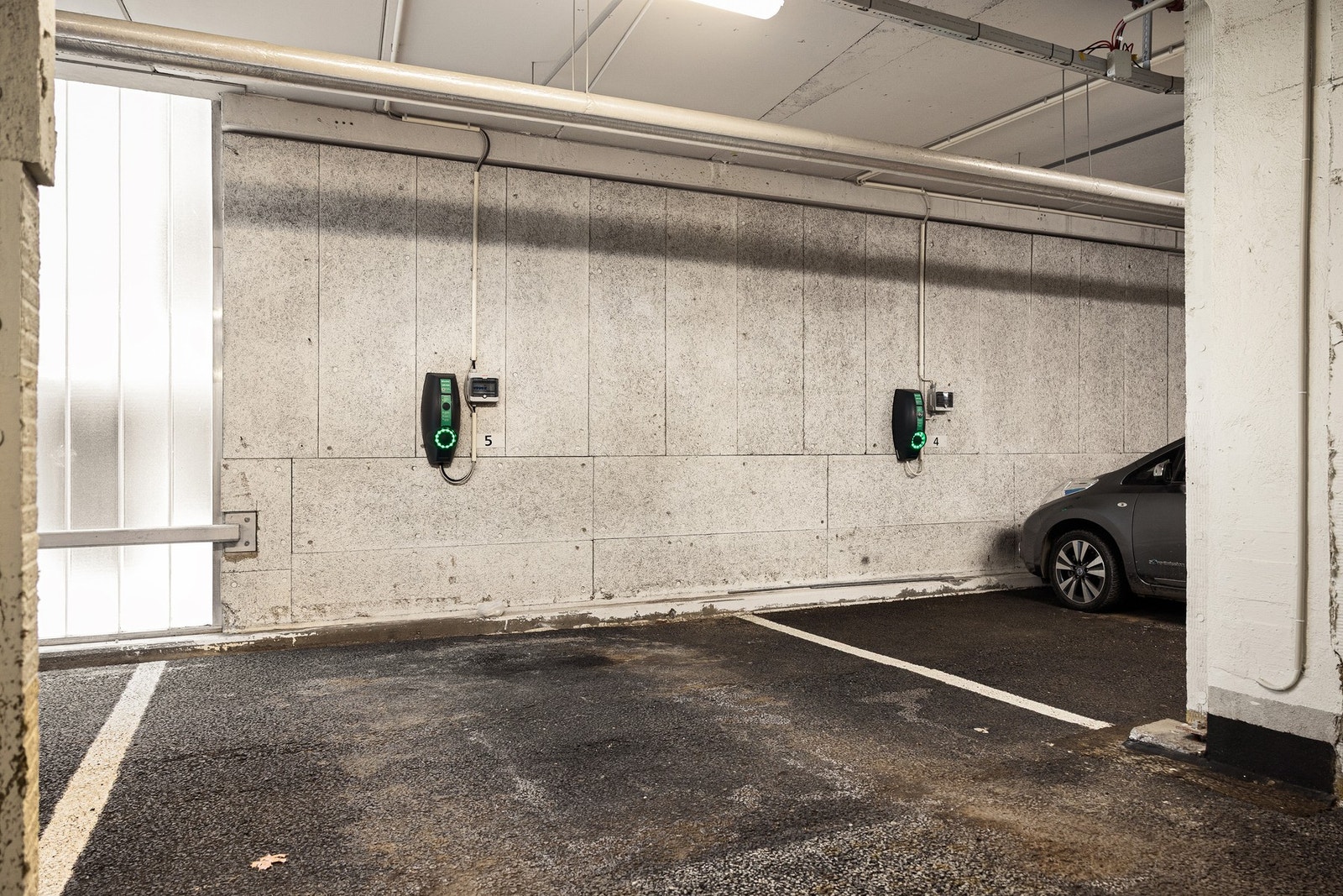 Romslig parkeringsplass med elbillader i innendørs garasjeanlegg. Galleribilde