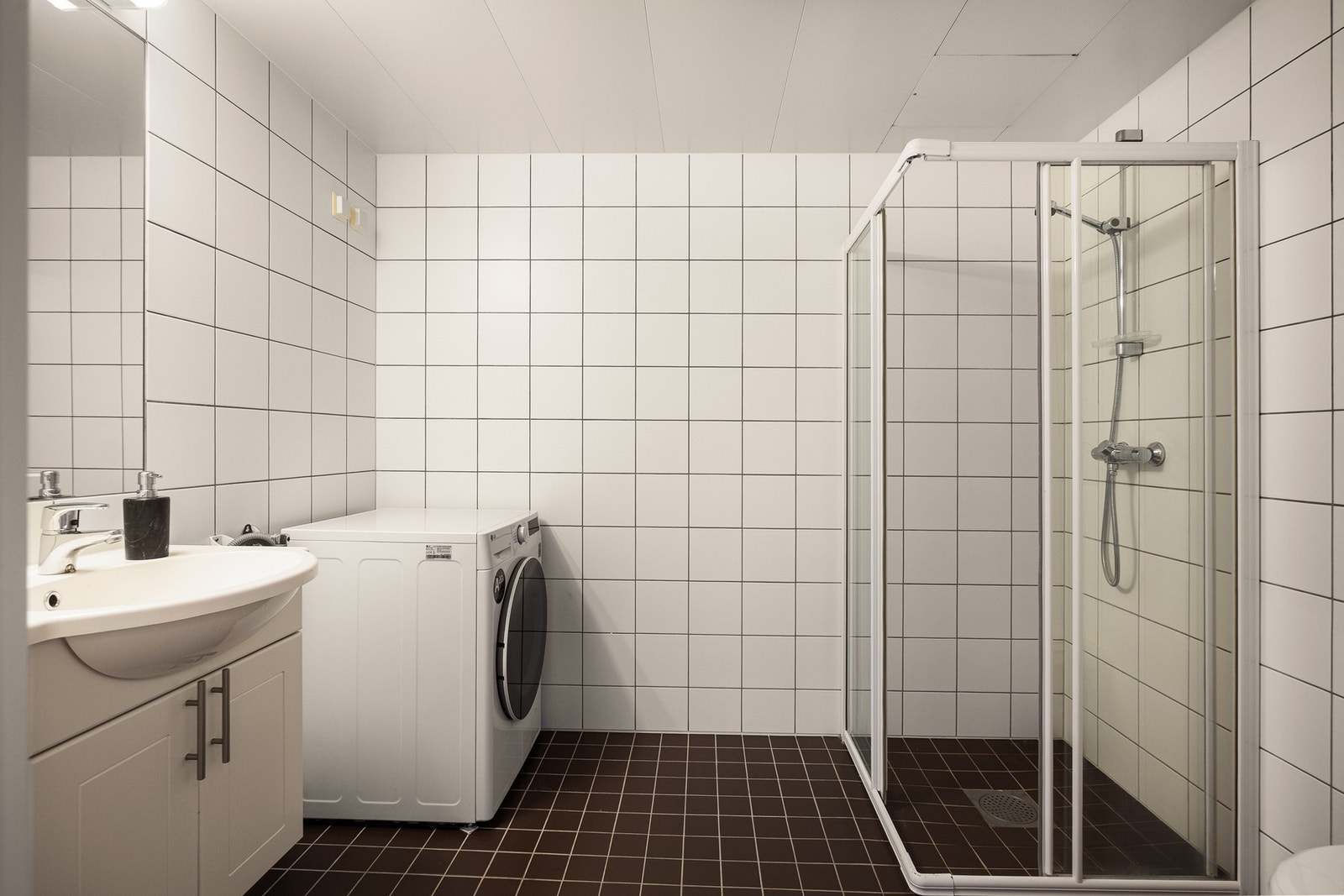 Rommet er utstyrt med servantskap med speil og integrert belysning, dusjhjørne og vegghengt toalett. Det er også plass til vaskemaskin og eventuell tørketrommel om ønskelig. Galleribilde