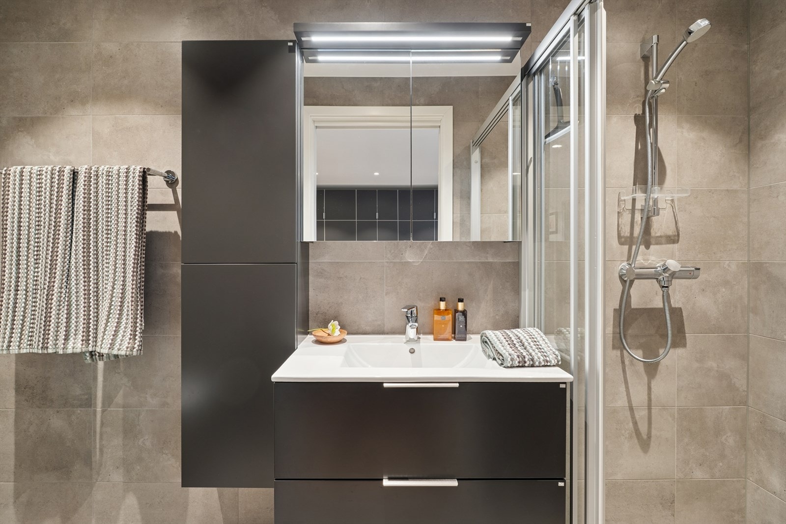 Badet er ellers utstyrt med dusjhjørne, vegghengt toalett og baderomsinnredning med god lagringsplass og nedfelt servant. Avtrekk via balansert ventilasjonsanlegg. Galleribilde