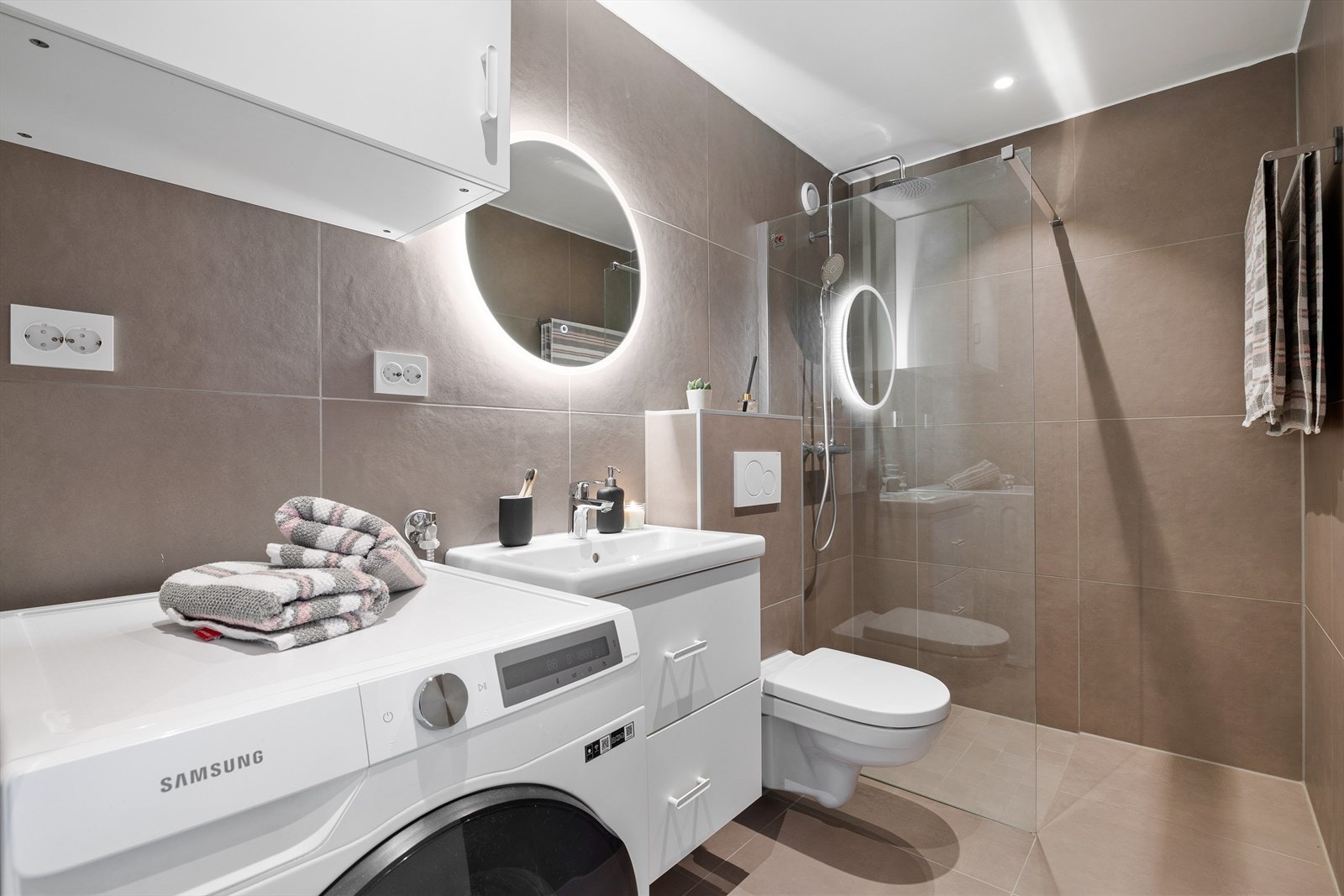 Det stilrene baderommet på 4,5 m² ble oppusset i 2024, og har et delikat flisvalg på gulv og vegger, samt varme i gulv som sikrer en lun start på dagen. Baderomsinnredningen har gunstige oppbevaringsmuligheter til håndduker og andre artikler. Galleribilde