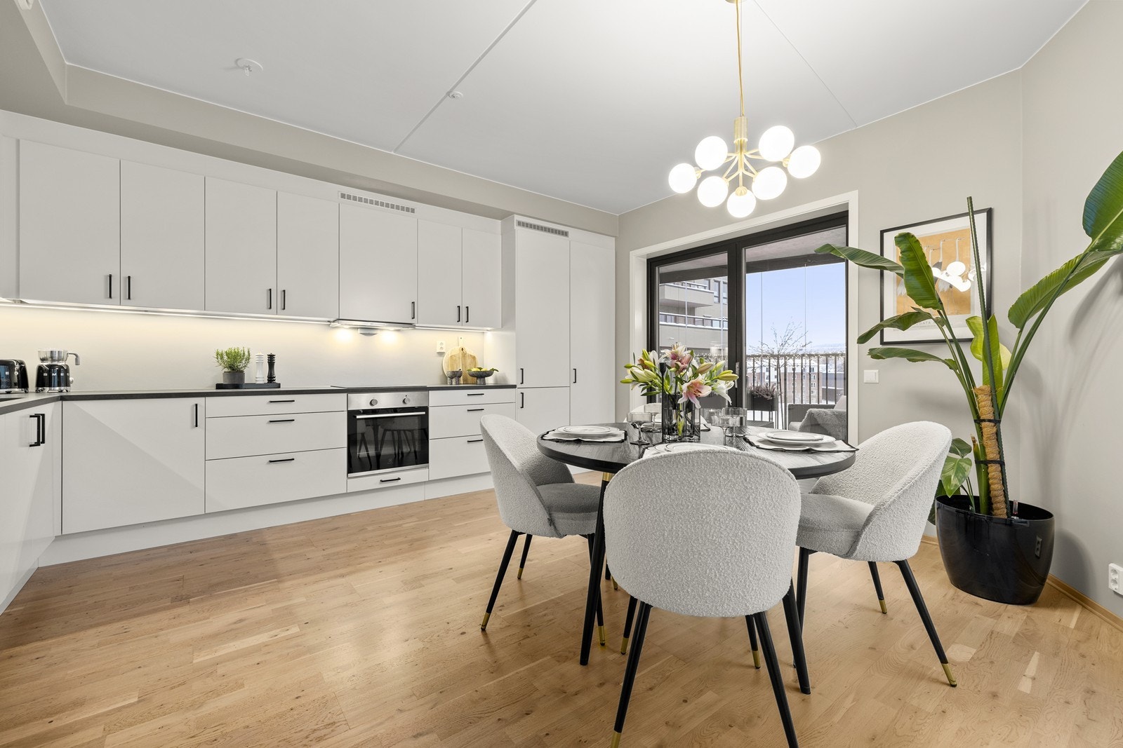 God belysning med downlights under overskapene på kjøkkenet og en moderne taklampe over spisebordet. Galleribilde