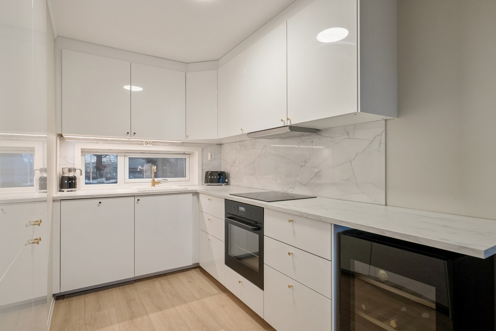 Kjøkkenet har hvite slette fronter og en laminert benkeplate, montert i 2023. Galleribilde