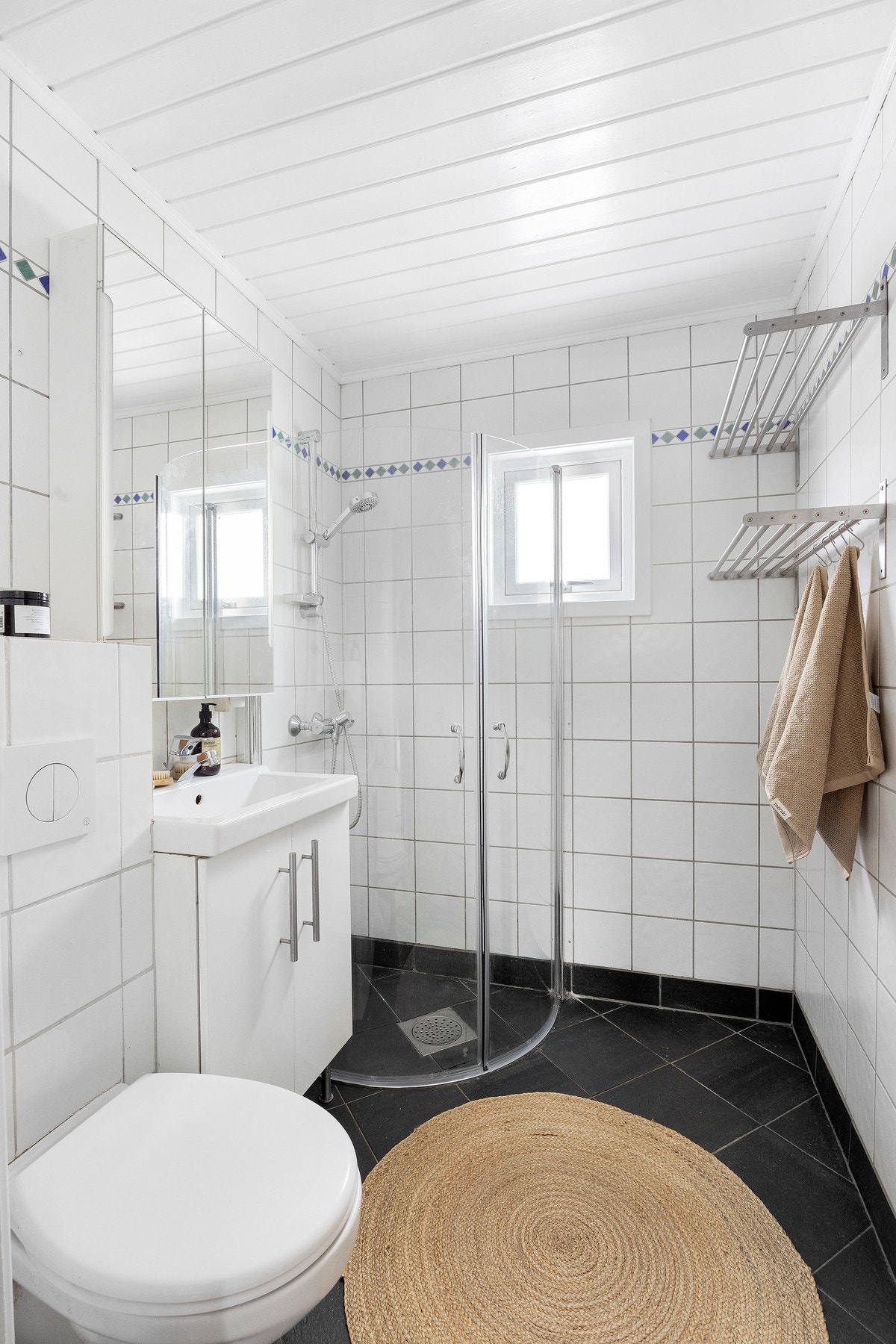 Flislagt bad med elektriske varmekabler som gir god komfort. Badet er innredet med dusjhjørne, vegghengt toalett, servant og speilskap Galleribilde