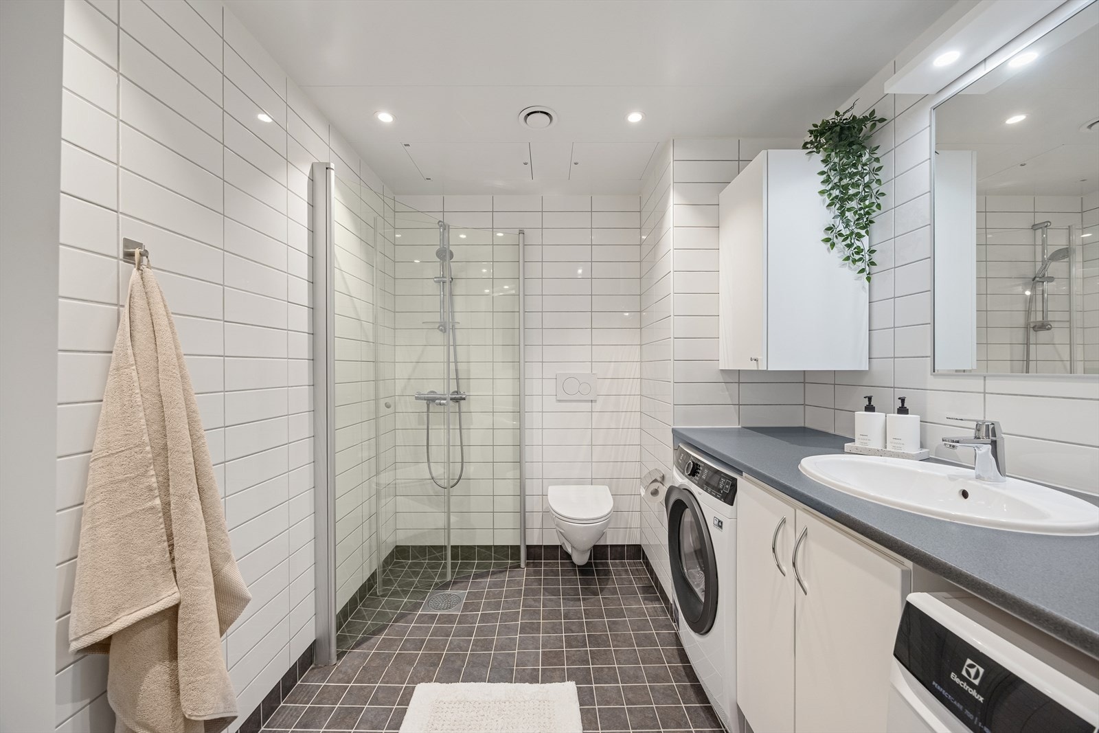 Badet har flislagte overflater på både vegger og gulv, med hvite metallplater i himlingen. Galleribilde