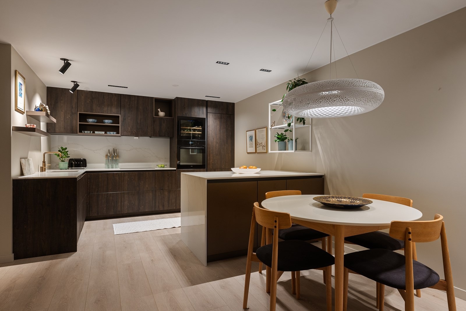 Delikat og eksklusiv kjøkkeninnredning fra Rotpunkt (2022) med folierte/finèrte fronter og kjøkkenøy mot stuen. Galleribilde