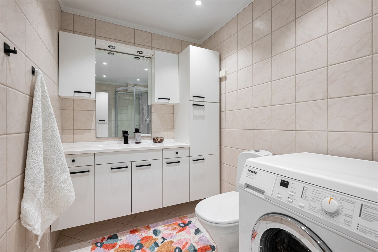 Baderom fra 2005 bestående av flislagt gulv med varmekabler, flislagte vegger og malt himling med downlights. Galleribilde