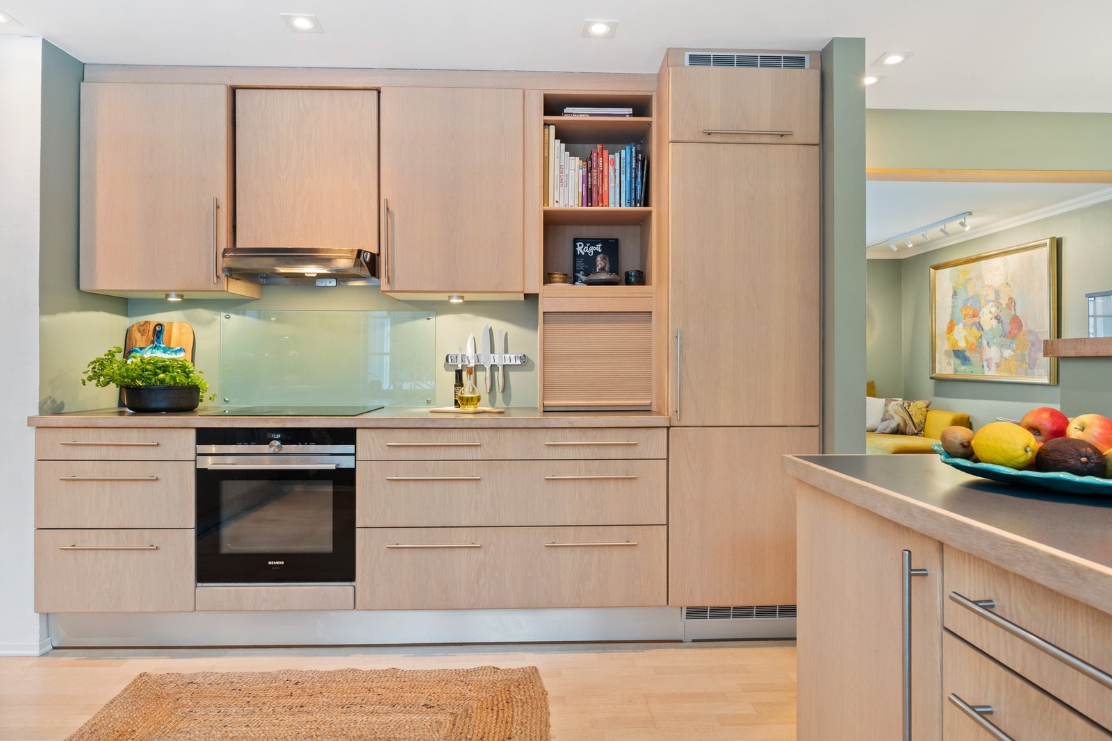 Det er god skap- og benkeplass i kjøkkenet og innredningen har slette fronter i eikefiner samt benkeplate av laminat med stålkum. Galleribilde