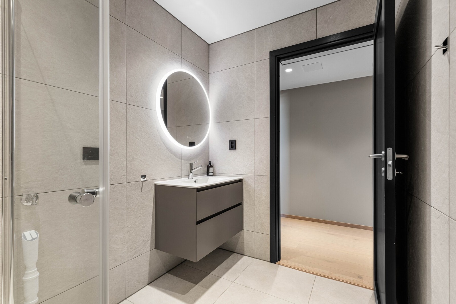 Badet har store gulv- og veggfliser, varmekabler og downlights. Galleribilde