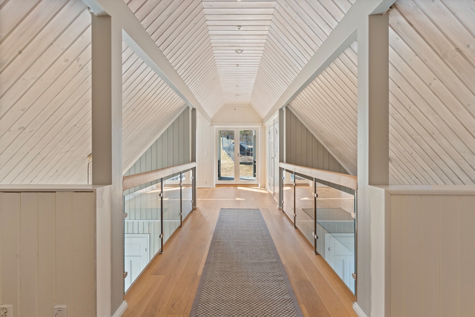 Her er det god takhøyde, store vindusflater og direkte utgang til hagen - noe som gir både rommet og etasjen en luftig og åpen følelse Galleribilde