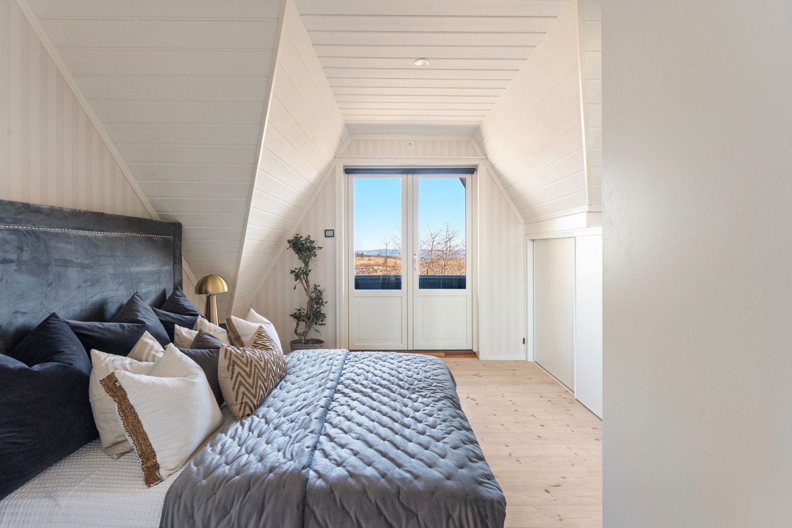 Det første soverommet er innbydende med skråhimling og lyse overflater. Rommet har god plass til dobbeltseng og øvrig møblement, og det er montert skyvedørsgarderobe Galleribilde