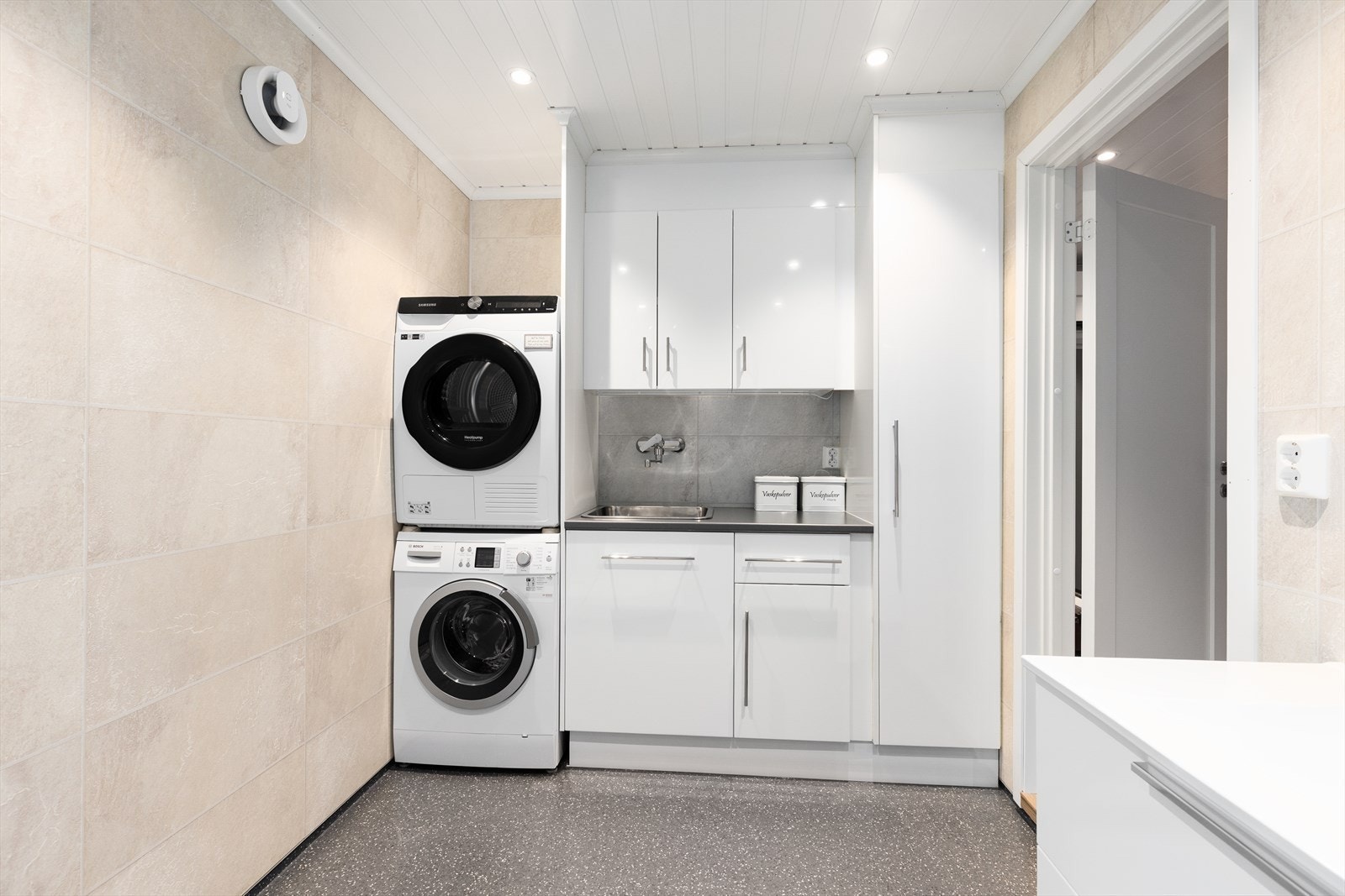 Rommet inneholder utslagsvask med skapinnredning, nedfelt servant, veggmontert toalett, dusjkabinett samt opplegg og plass for vaskemaskin. Avtrekk via elektrisk, fuktstyrt vifte i yttervegg. Galleribilde