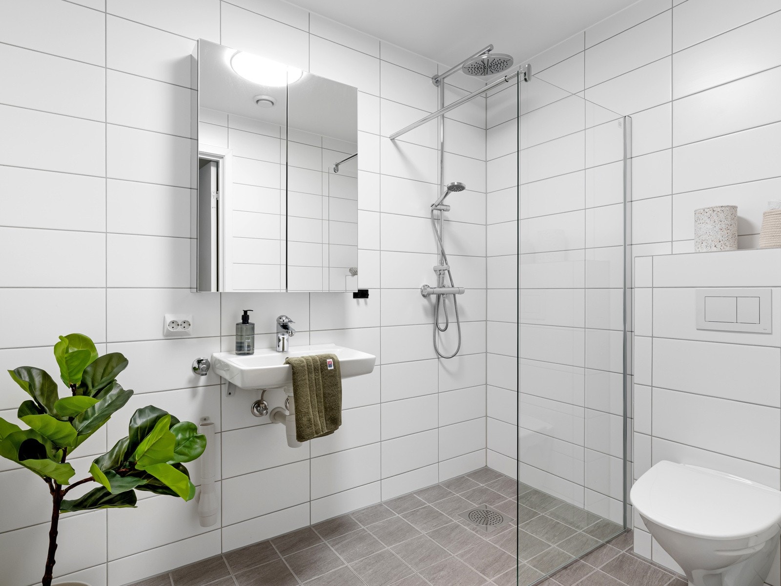 Badet i 1. etasje fremstår som funksjonelt og innbydende, med fliser på gulv og vegger. Galleribilde