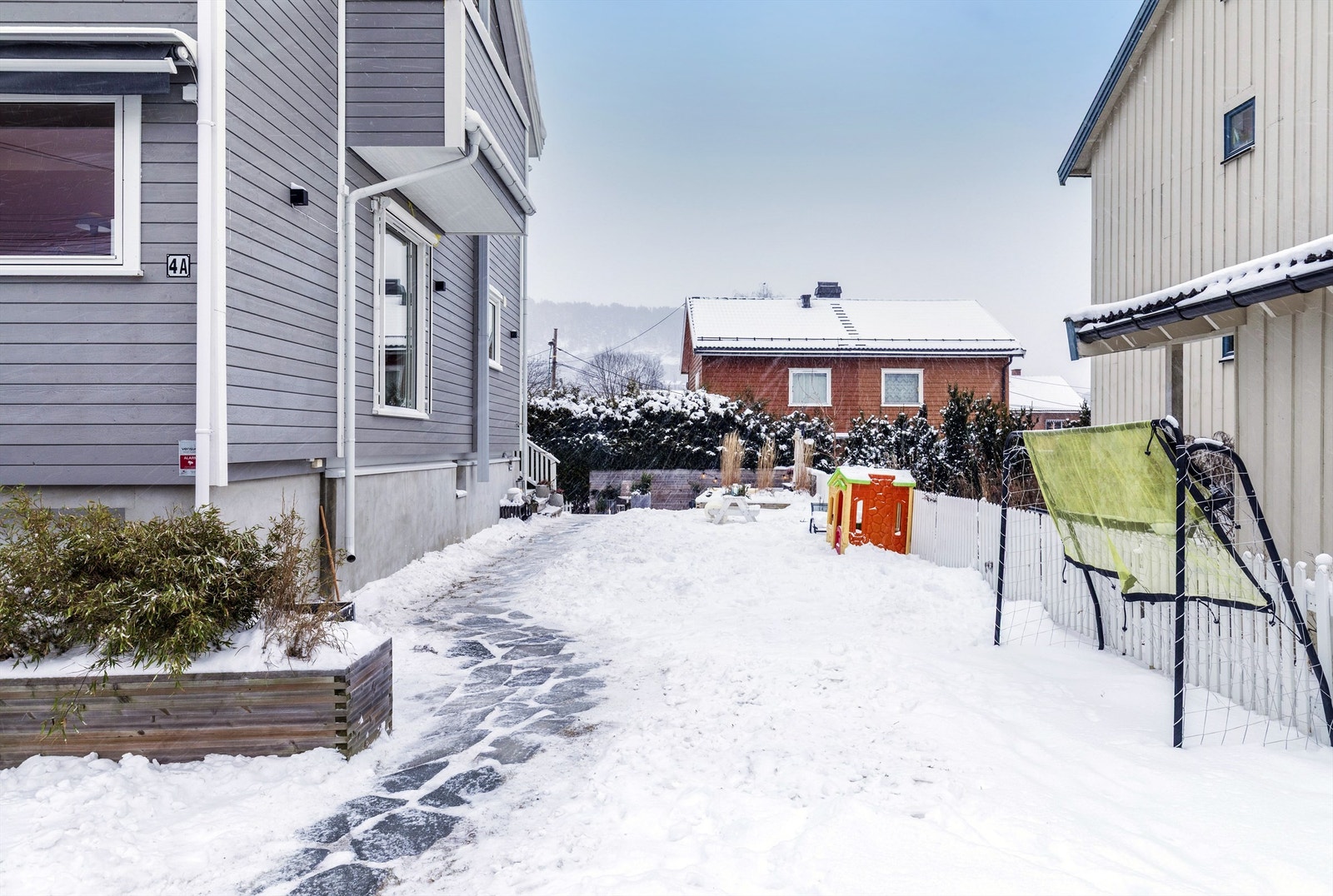 Hagen strekker seg fra forsiden av huset, med gressplen og markterrasse Galleribilde