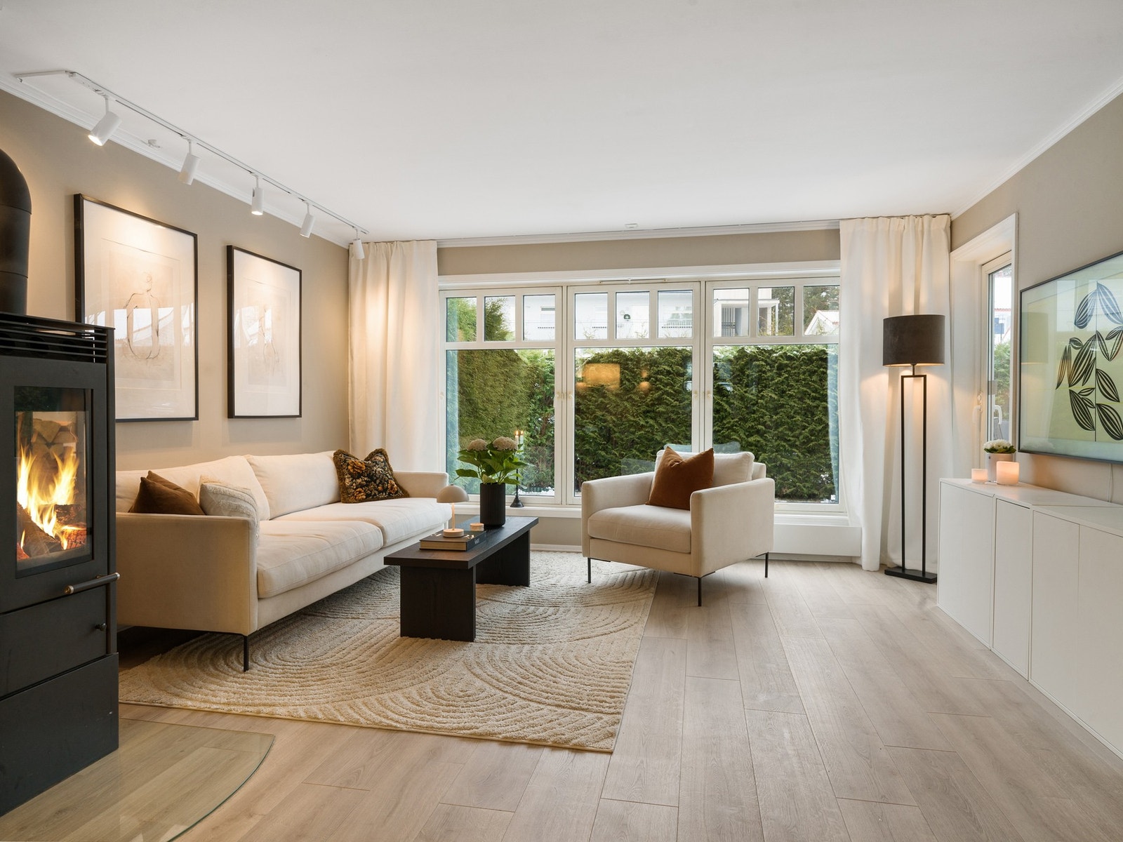 Lys og delikat stue med peisovn og store vindusflater mot vest. Galleribilde