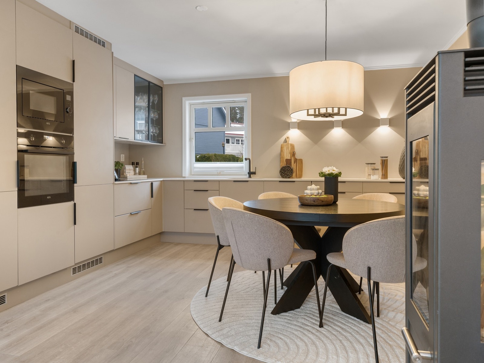 Takhøy kjøkkeninnredning med beige, glatte fronter og overskap med mørke glassfronter. Galleribilde