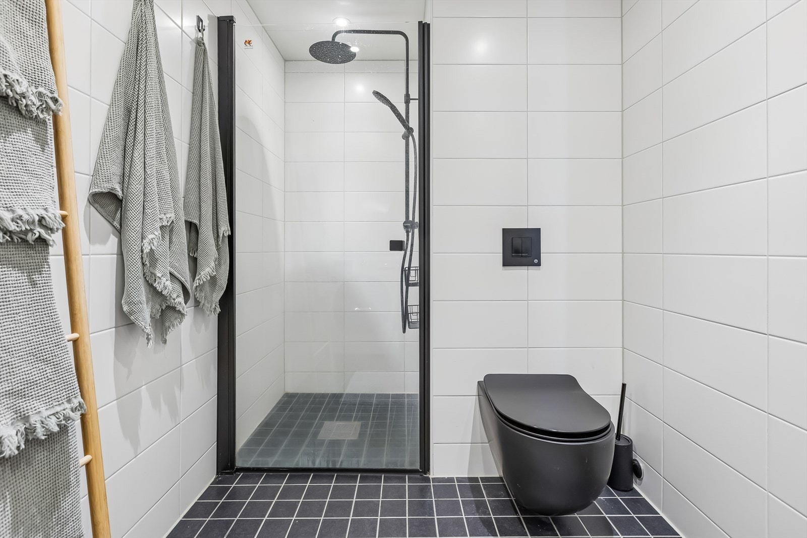 Dusjhjørne med innfellbare glassdører og vegghengt toalett for enkelt renhold. Galleribilde