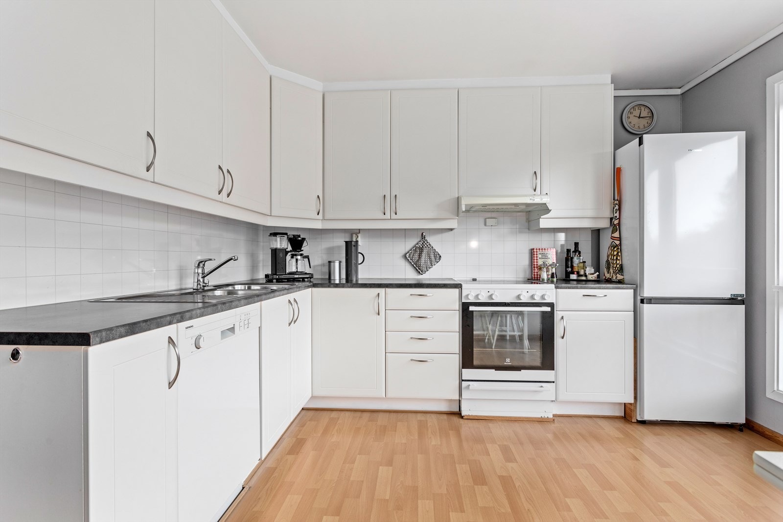 Kjøkkenet med standard frå byggjeår har kvite glatte frontar og mørk benkeplate av laminat. Galleribilde