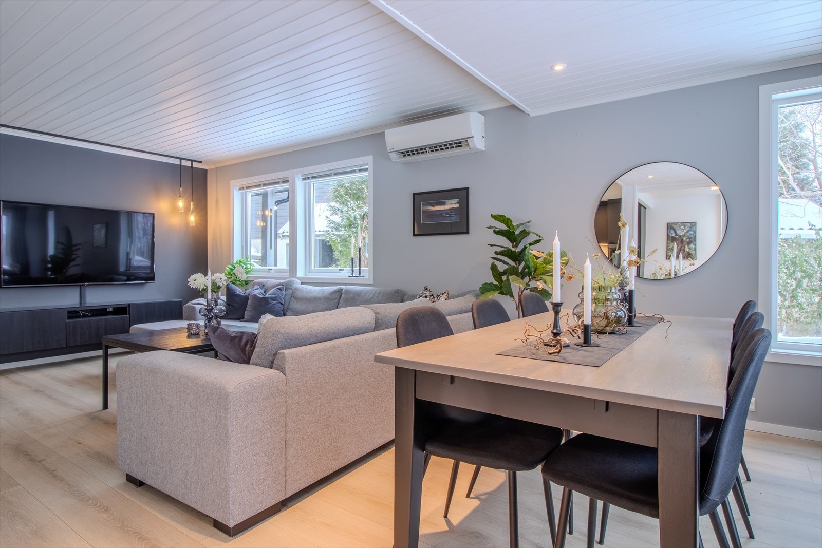 Lys og romslig stue med store vindusflater og god plass til både sofa- og spisegruppe. Varmepumpe på vegg. Galleribilde