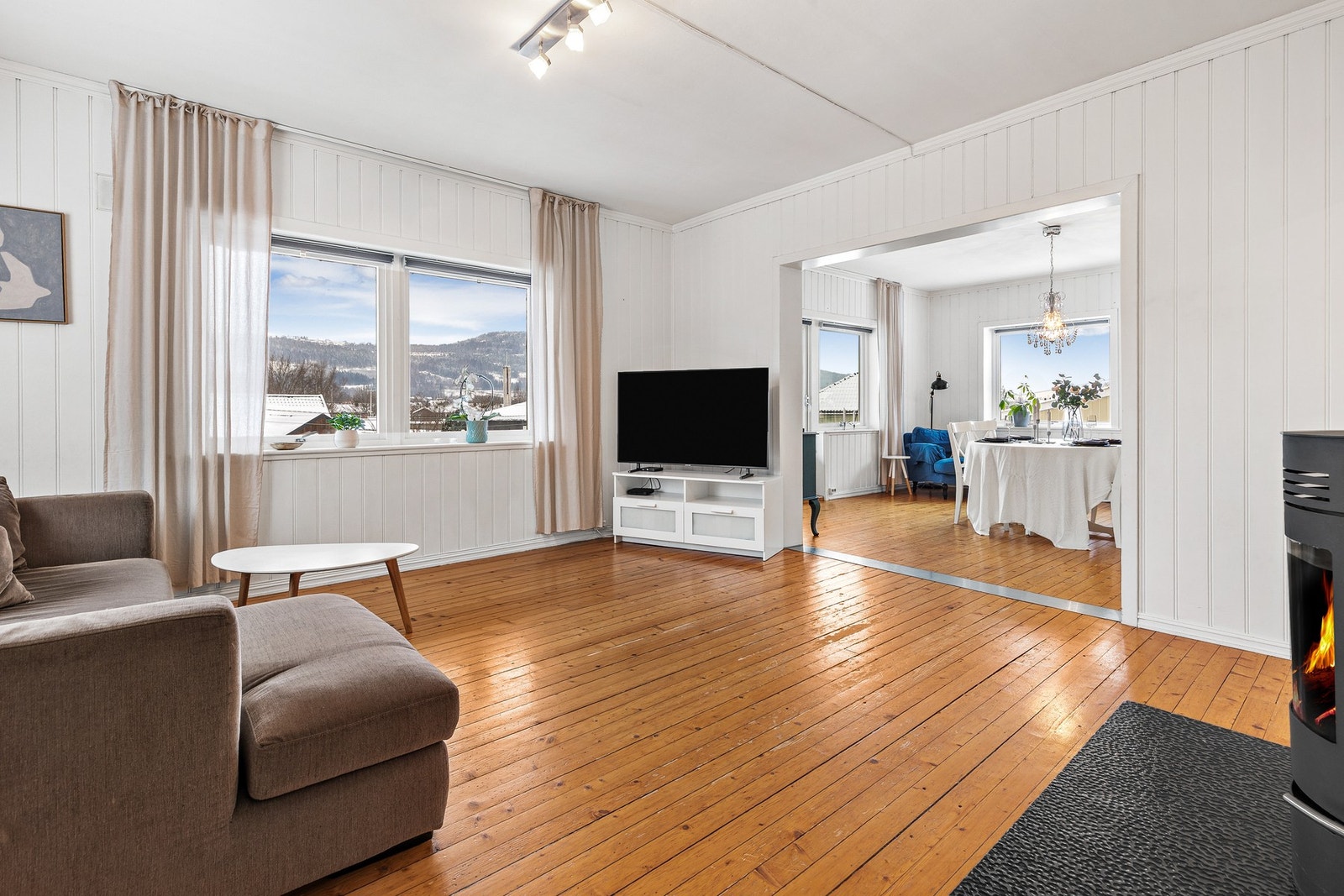 Stuen fremstår som lyst og luftig, med store vindusflater på tre sider som gir rikelig med naturlig lys Galleribilde