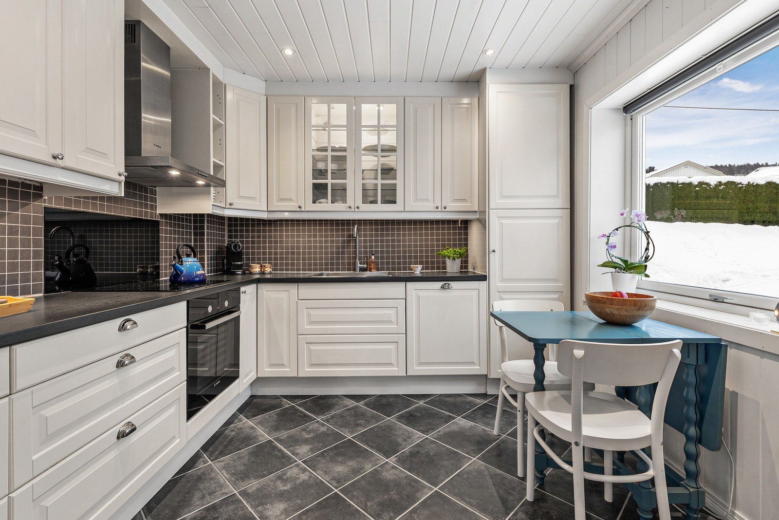 Ikea-kjøkkeninnredning fra 2012 med hvite, profilerte fronter og benkeplate i laminat med nedfelt oppvaskkum og ett-greps blandebatteri Galleribilde