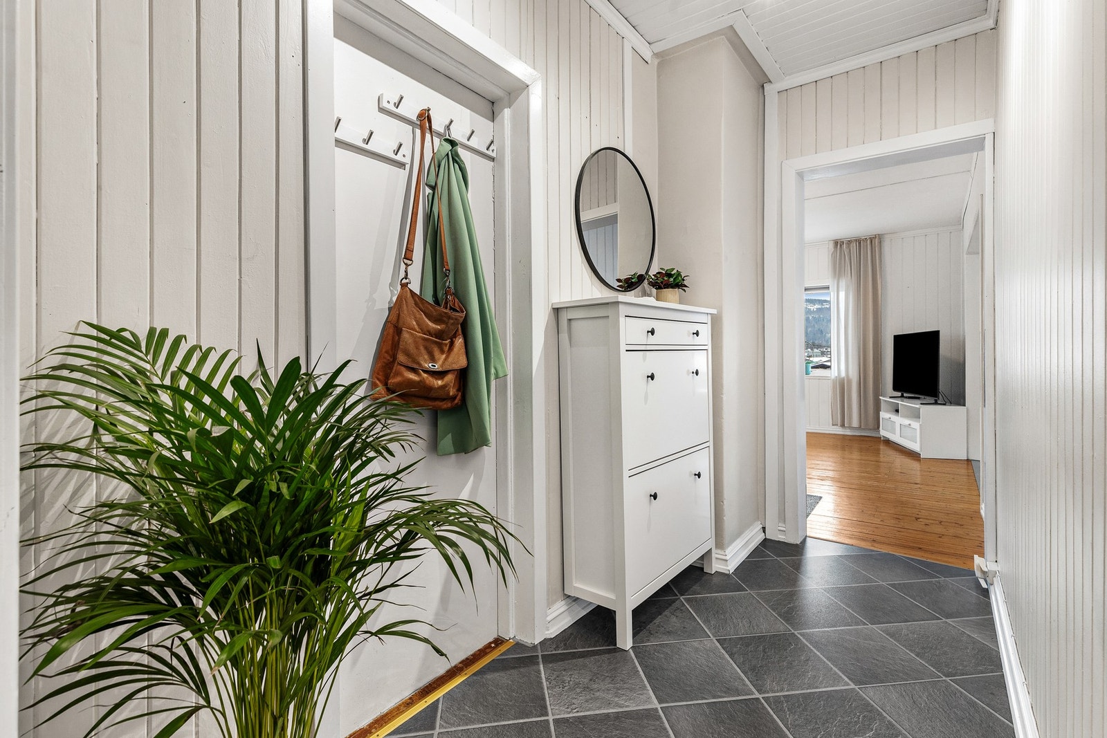 Entré med laminat på gulv og malte panelbord på vegger og i himling Galleribilde