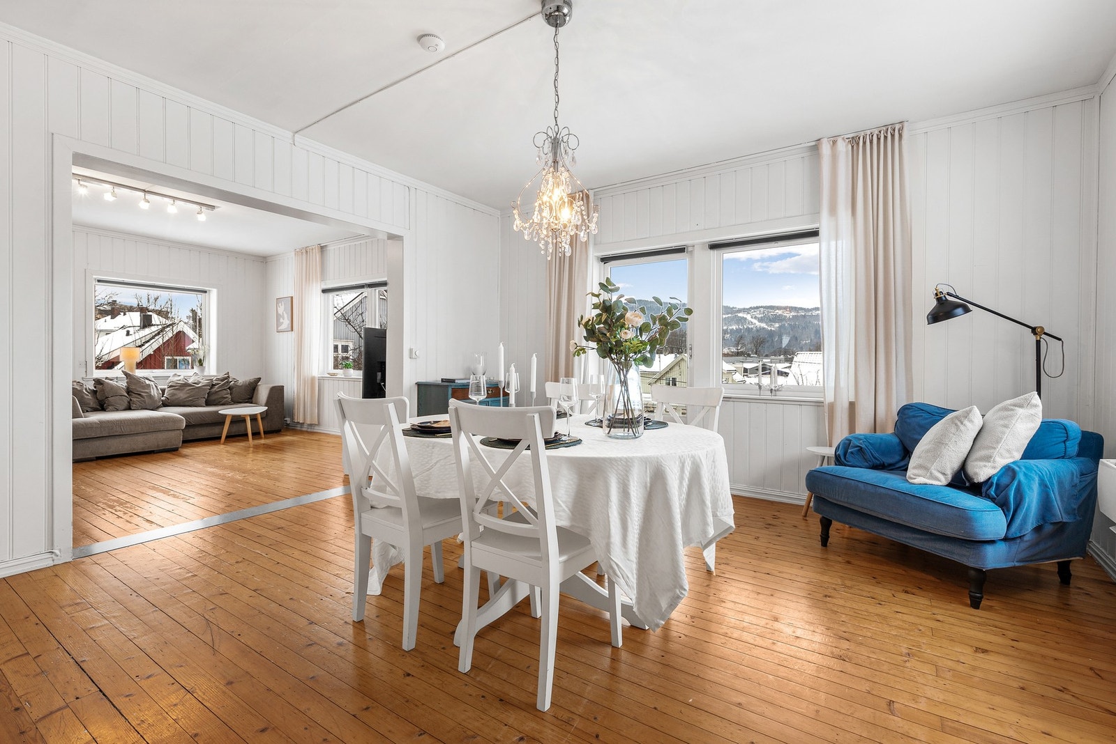 Stue og spisestue med heltre gulvbord, panelplater på veggene og slette flater i himling Galleribilde