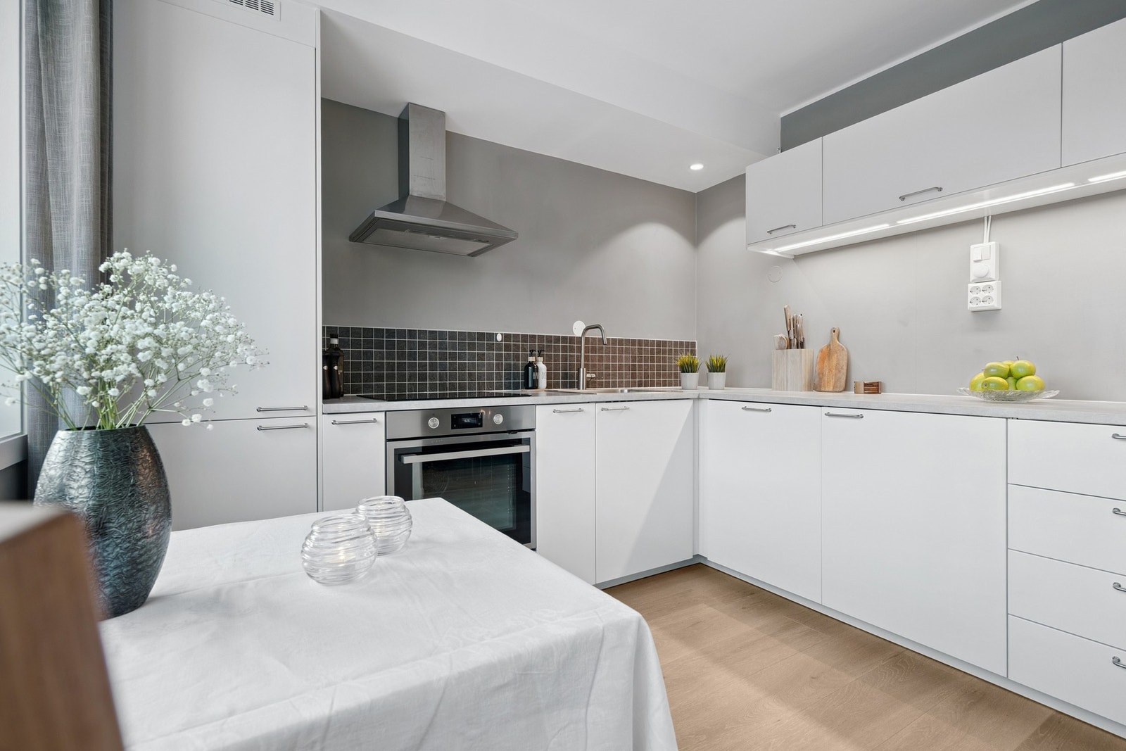 Kjøkkenet er komplett med integrerte hvitevarer, blant annet stekeovn, platetopp, oppvaskmaskin og kjøleskap med fryser, og gir et praktisk og stilrent arbeidsområde. Galleribilde