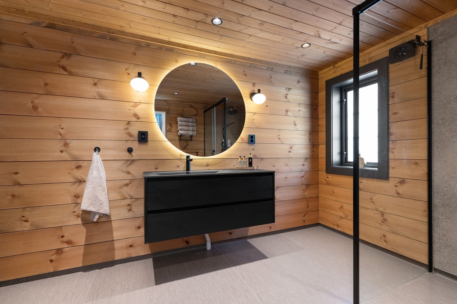 Hyttas romslige bad er fra 2023, og her er vegg kledd med beiset trepanel, baderomsplater i dusjhjørne Galleribilde