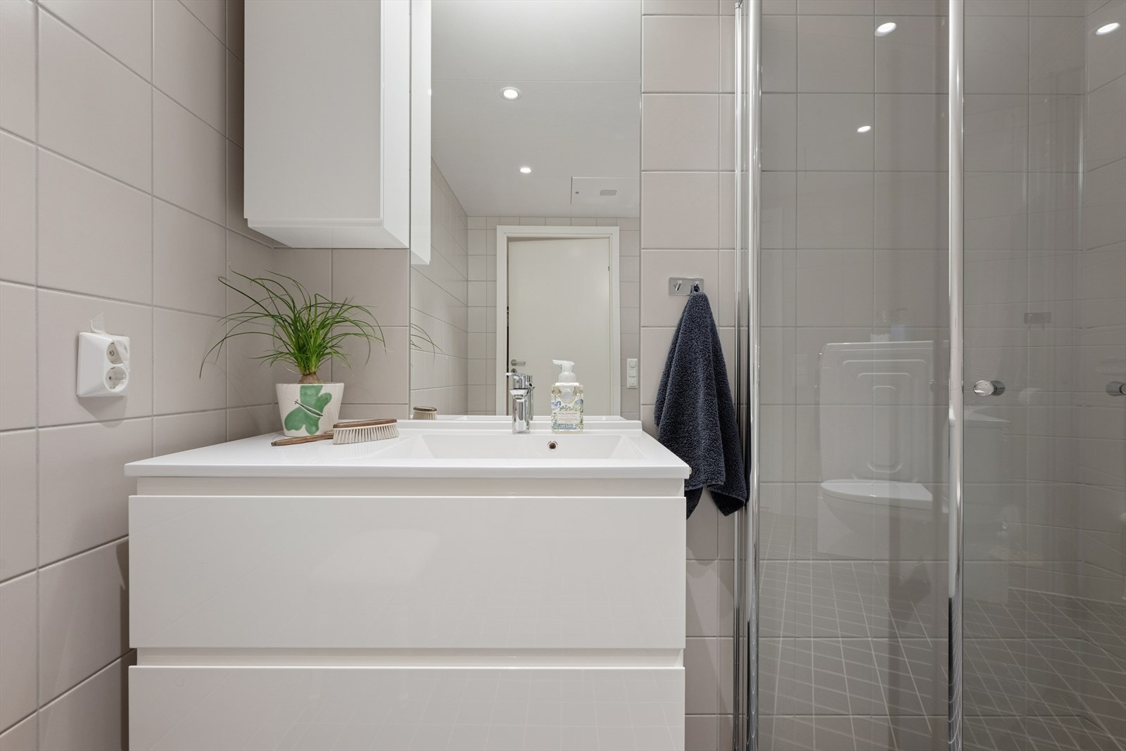 Baderommet har en moderne innredning med nedfelt servant med skuffer, vegghengt toalett og innfellbare dusjvegger. Galleribilde