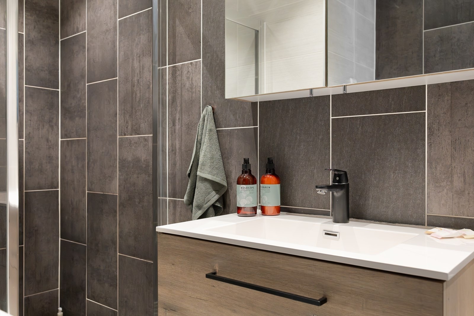 Badet er innredet med vegghengt toalett, servant med skap, speil og belysning, samt opplegg for vaskemaskin. Galleribilde