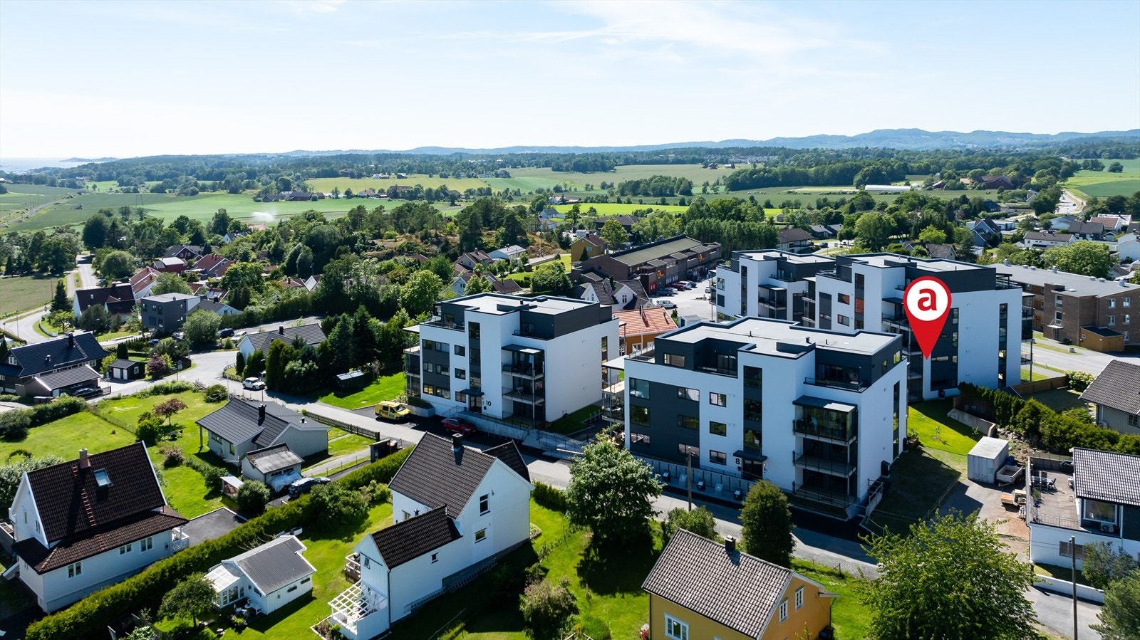 Dronefoto. Leiligheten er gjennomgående i bygget og har balkong både inn mot tunet og mot vest Galleribilde