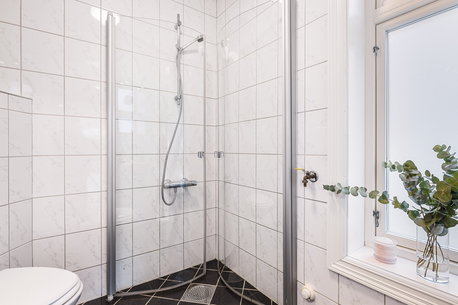 Rommet er innredet med vegghengt toalett, dusjhjørne med glassdører samt servant med over- og underskap som gir god oppbevaringsplass. Galleribilde