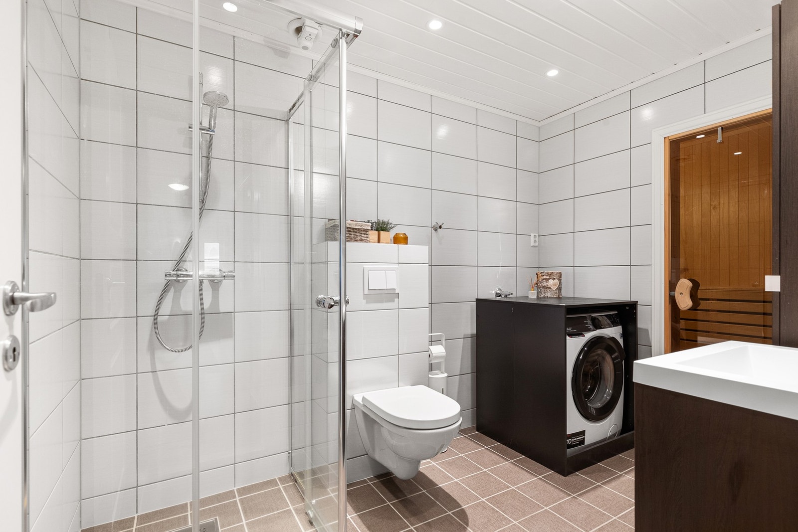 Hovedbad med delikate fliser, vegghengt toalett, downlights og plass for vaskemaskin Galleribilde