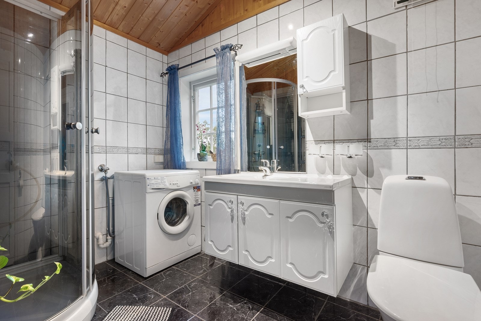 Bad med dusjkabinett, wc, servant og opplegg for vaskemaskin. Galleribilde