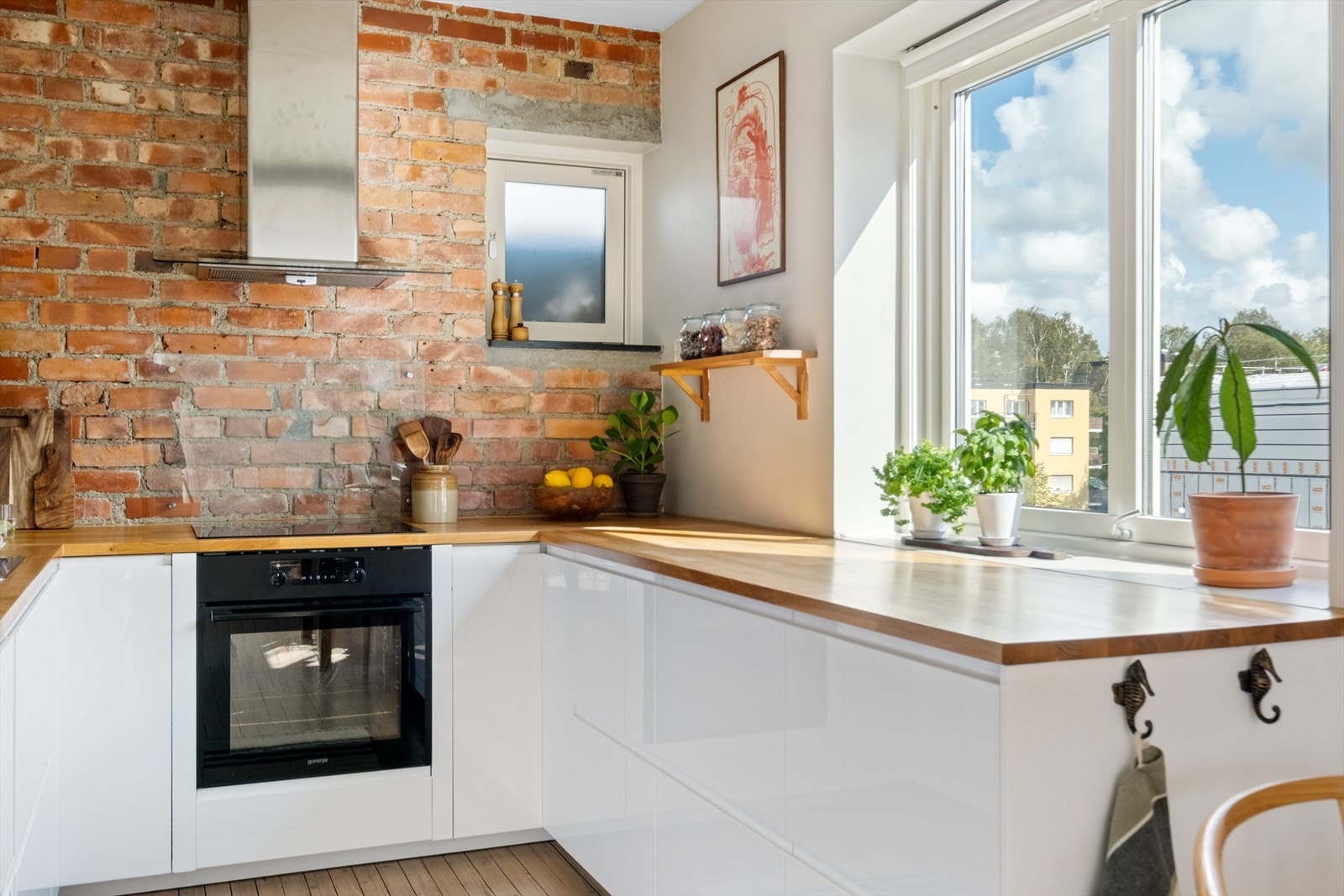 Moderne kjøkkeninnredning med glatte fronter, heltre benkeplate med nedfelt vaskekum, fliser, splashboard og belysning over benkeplaten, samt takhøye overskap. Galleribilde